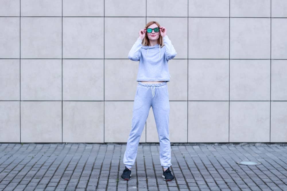 A woman wearing a loose pair of gray sweatpants.