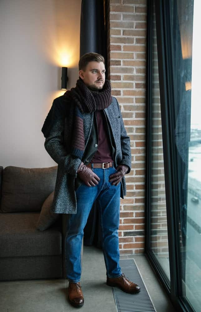 A man wearing a pair of jeans with his coat.