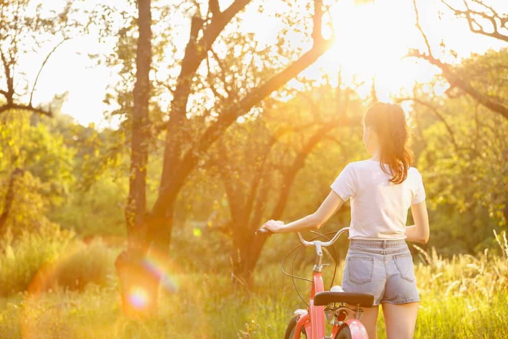 A woman with her bike wearing a pair of classic denim shorts.