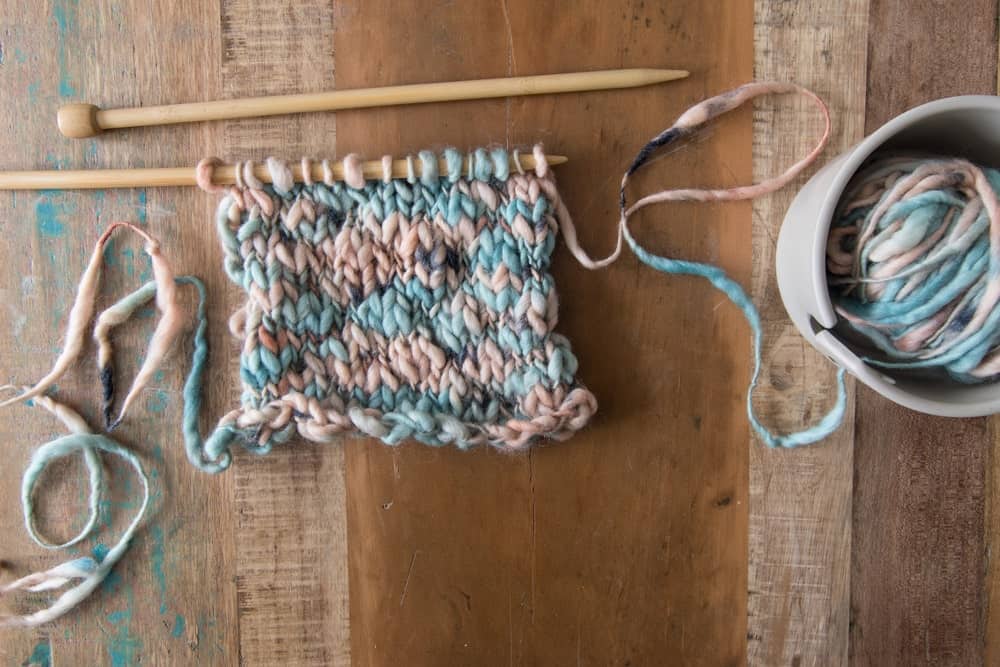 An unfinished knitting project using thick-thin yarn.