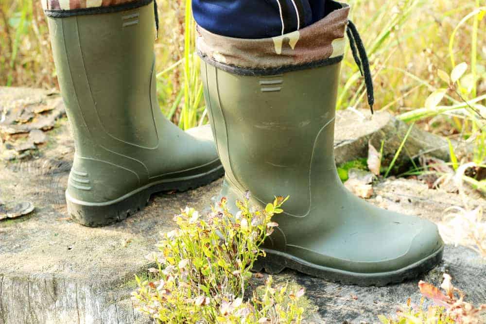 Man in green rubber boots standing on the rocks.