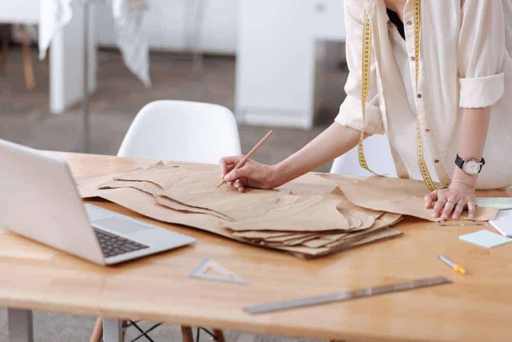 Woman writing on a dress pattern.