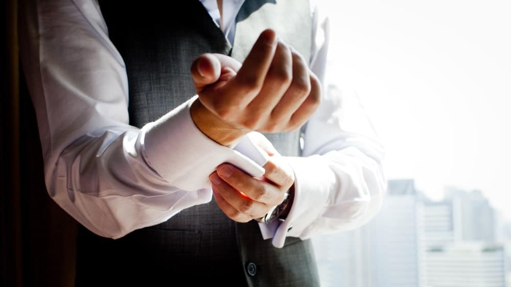 This si a close look at a man adjusting his cuffs.