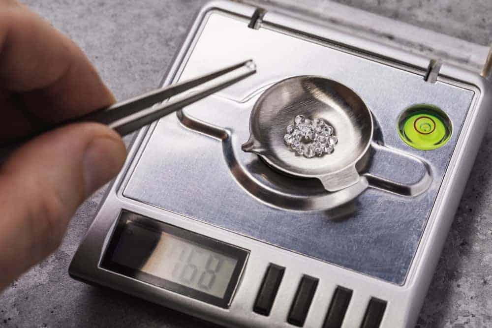A bunch of diamonds on a carat weighing scale.