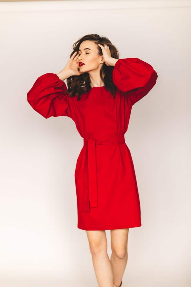 A woman wearing a lovely red dress that has lantern sleeves.