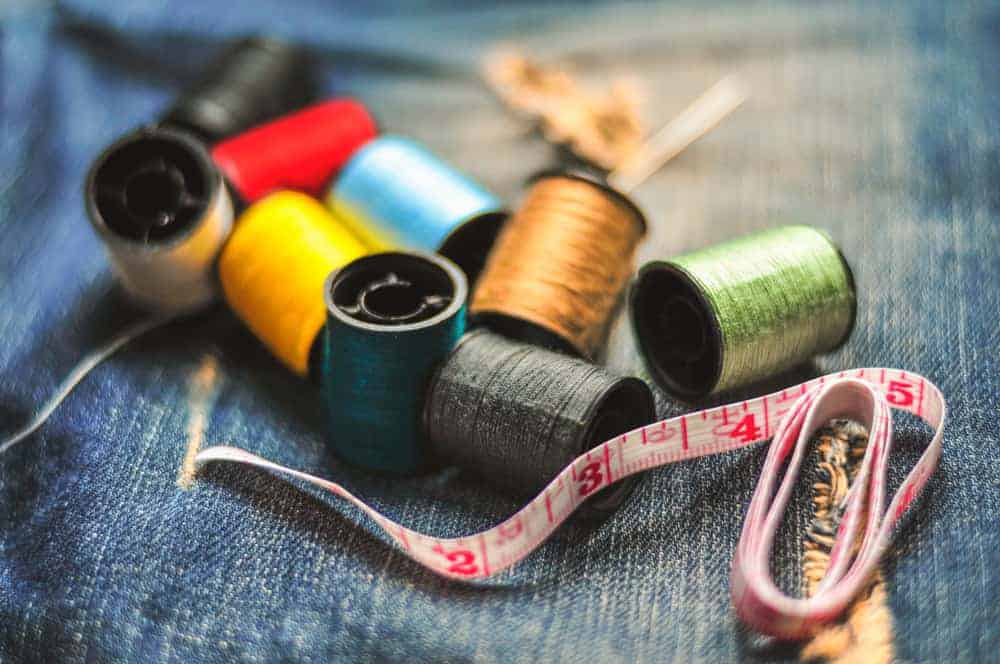 Various sewing essentials on a denim fabric.