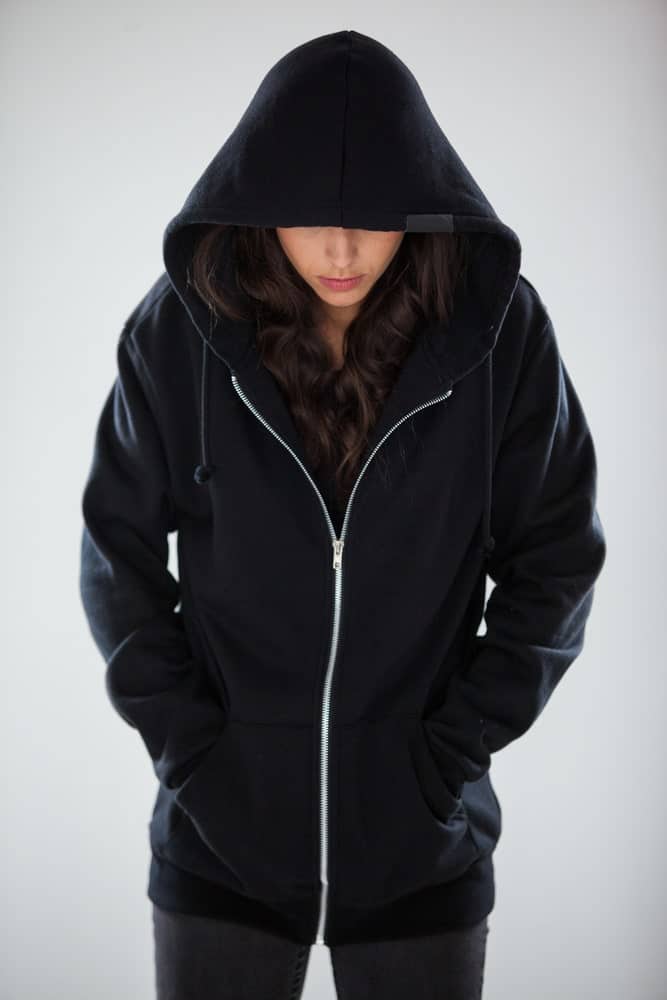 A woman wearing a zippered sweatshirt with hood.