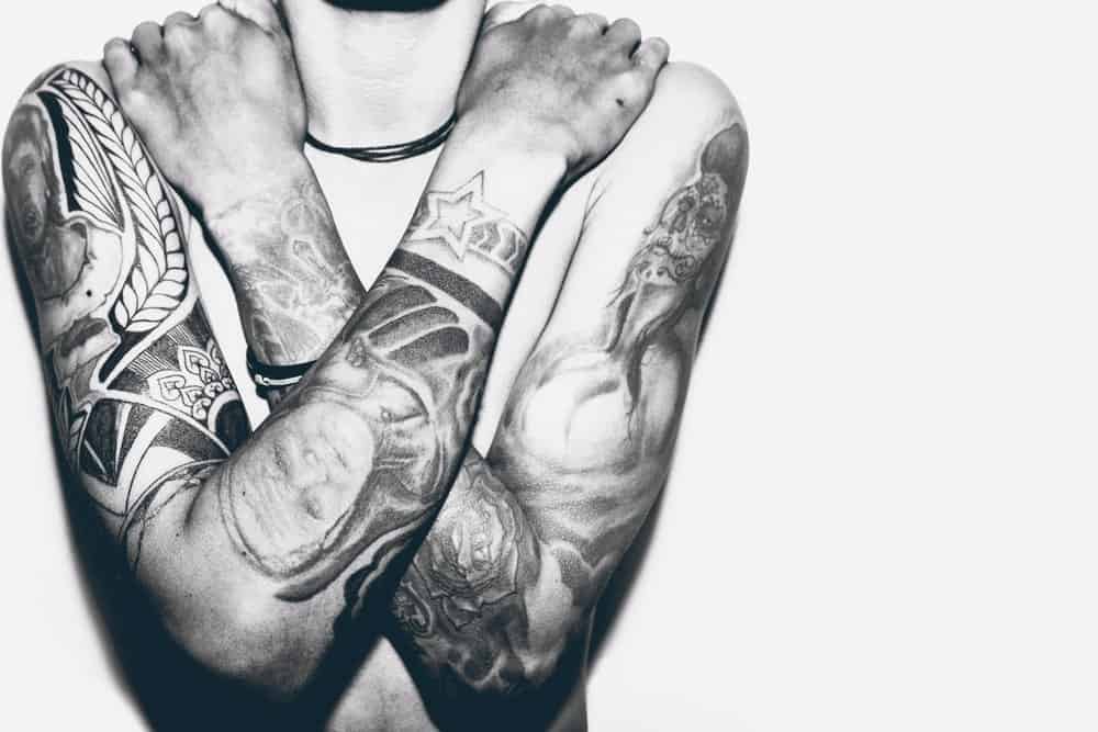 A close look at a man with portrait tattoos on his arms.
