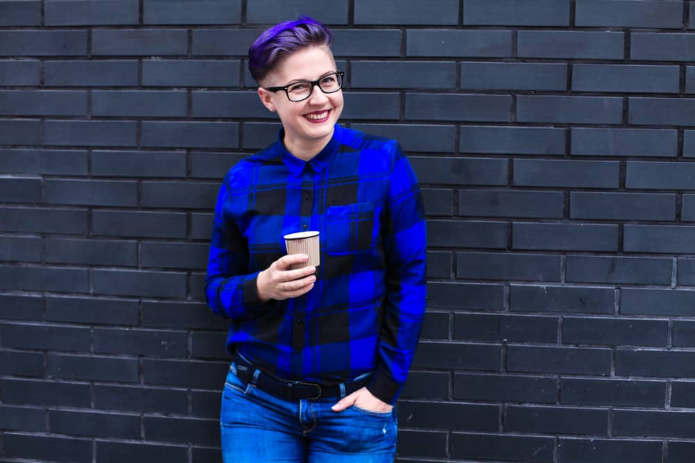 Woman wearing blue checkered long sleeves, denim pants, and eyeglasses.