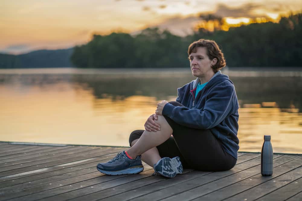 Woman in an athleisure wear stretching near the lake.
