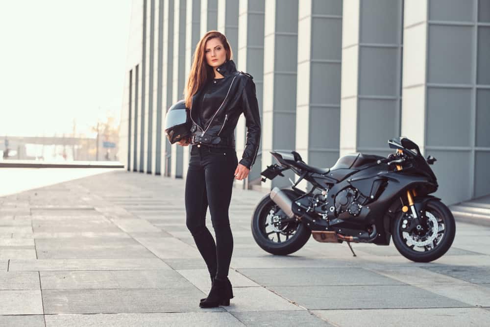 Female biker holding a helmet.