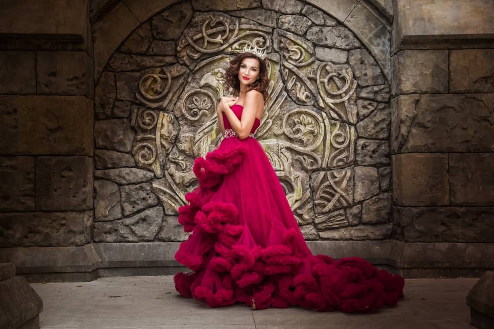 Woman wearing a luxurious red evening dress and a crown.