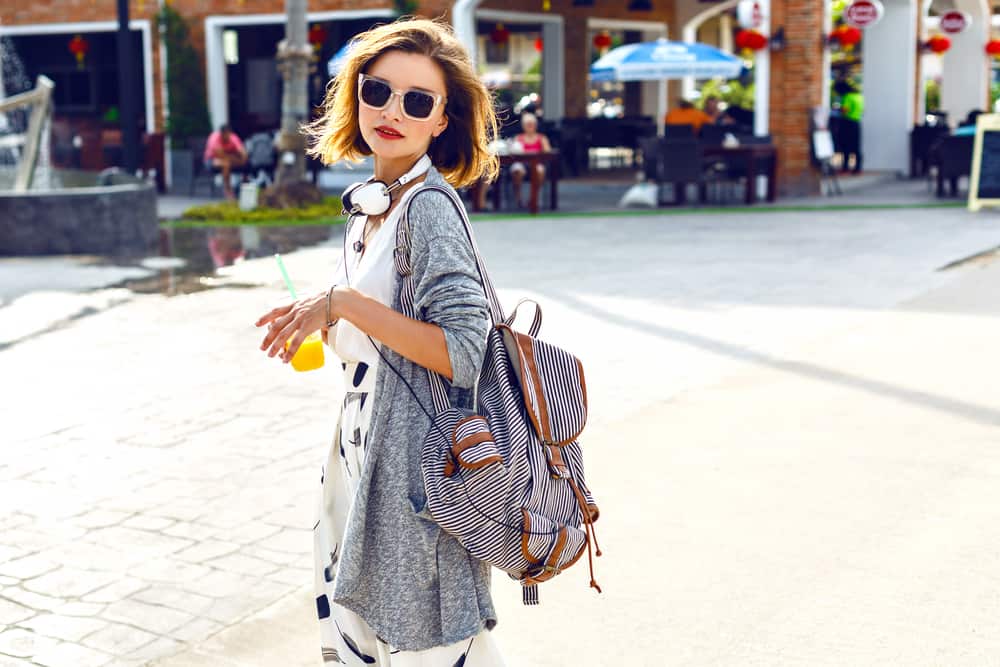 Woman in a gamine style outfit with backpack walking on the street.