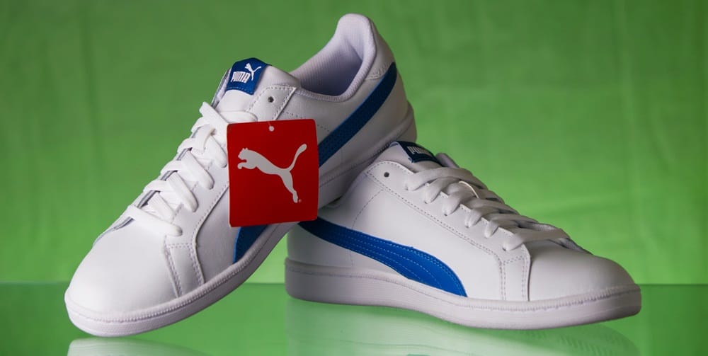A pair of white Puma sneakers on display.