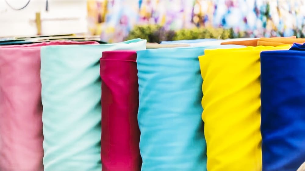 A close look at various rolls of fabrics on display.