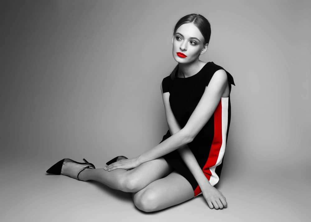 This is a woman wearing a black Shift Dress with red and white accents on the side.