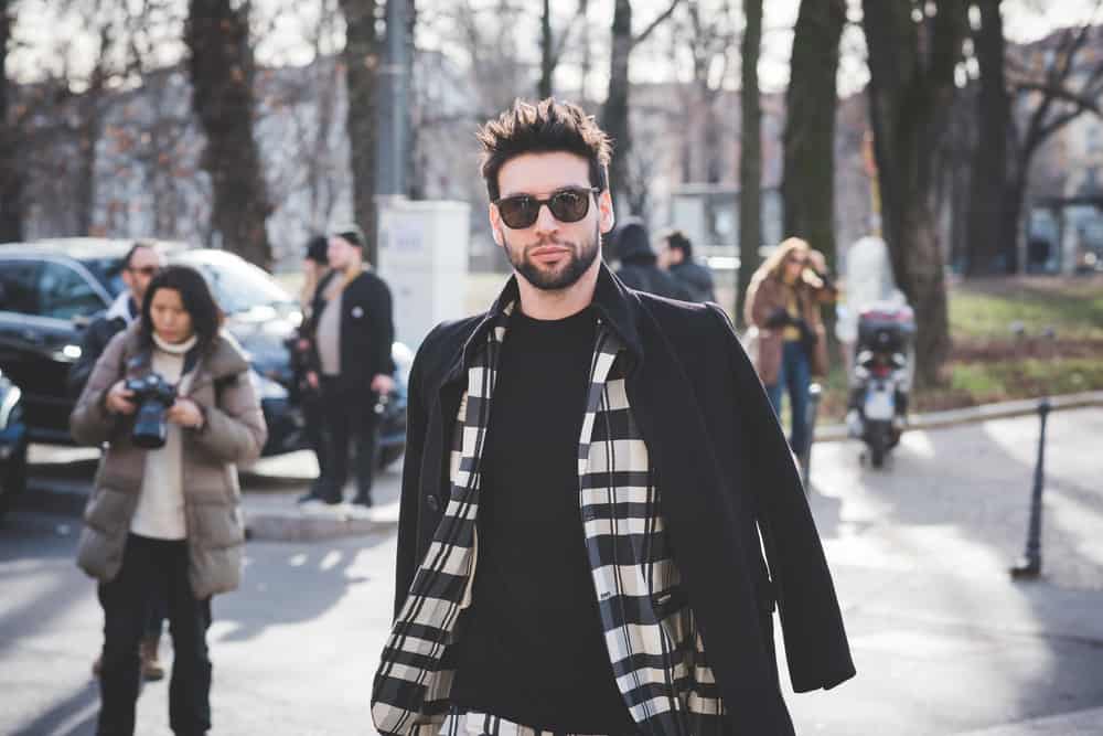 Man wearing shades, black coat, and plaid polo.