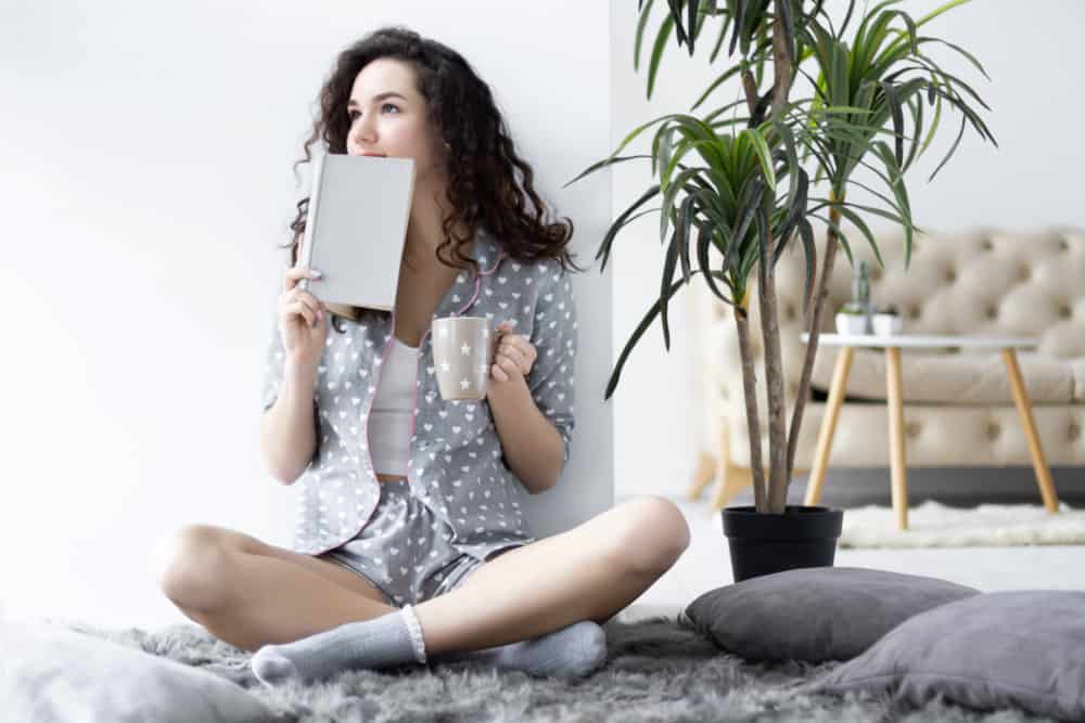A woman lounging by the living room wearing shortie pajamas.