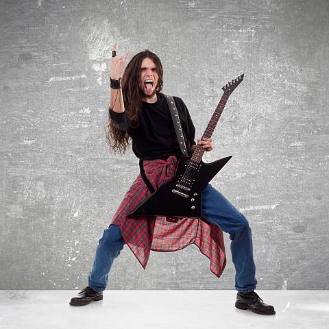 Long haired guitarist making a rock hand gesture.