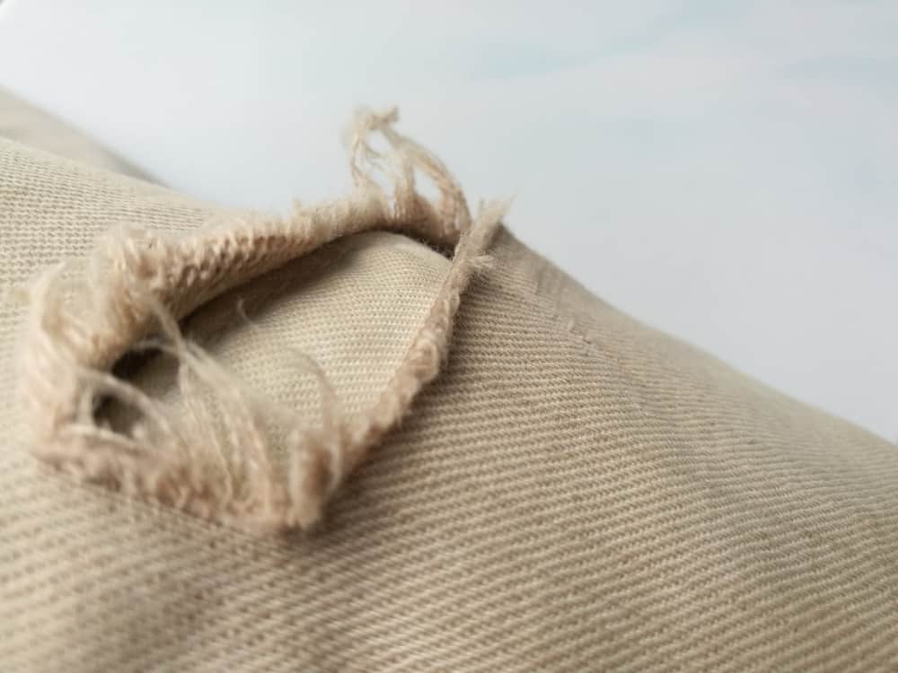 This is a close look at a pair of jeans with a frayed tear.