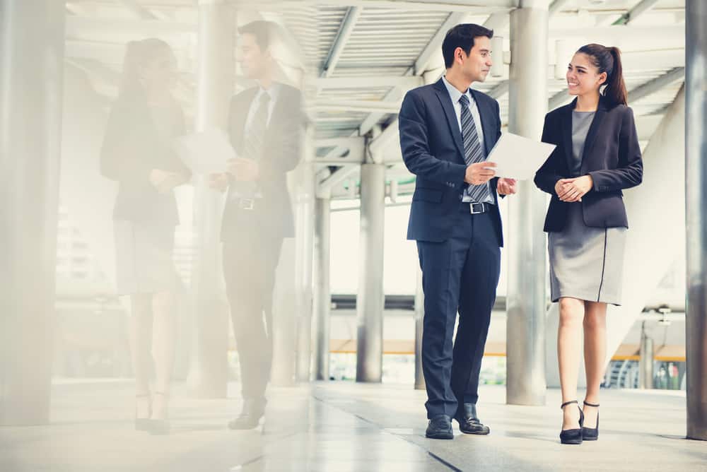 Businessman and businesswoman discussing work while walking.