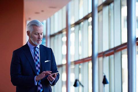 Senior businessman texting inside the office.