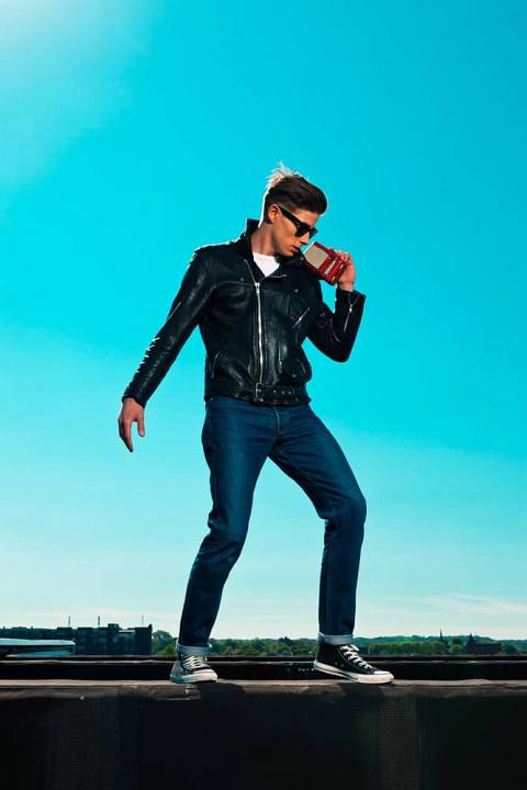 Man in a rockabilly outfit holding a portable radio.
