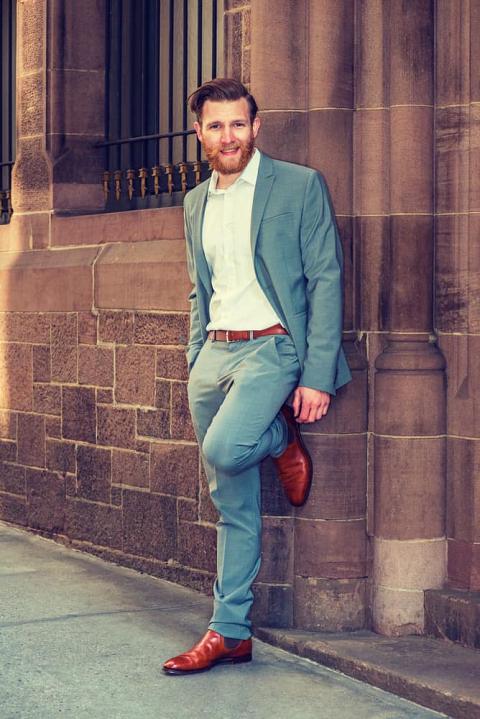 Man in a semi-formal clothes standing against vintage wall.