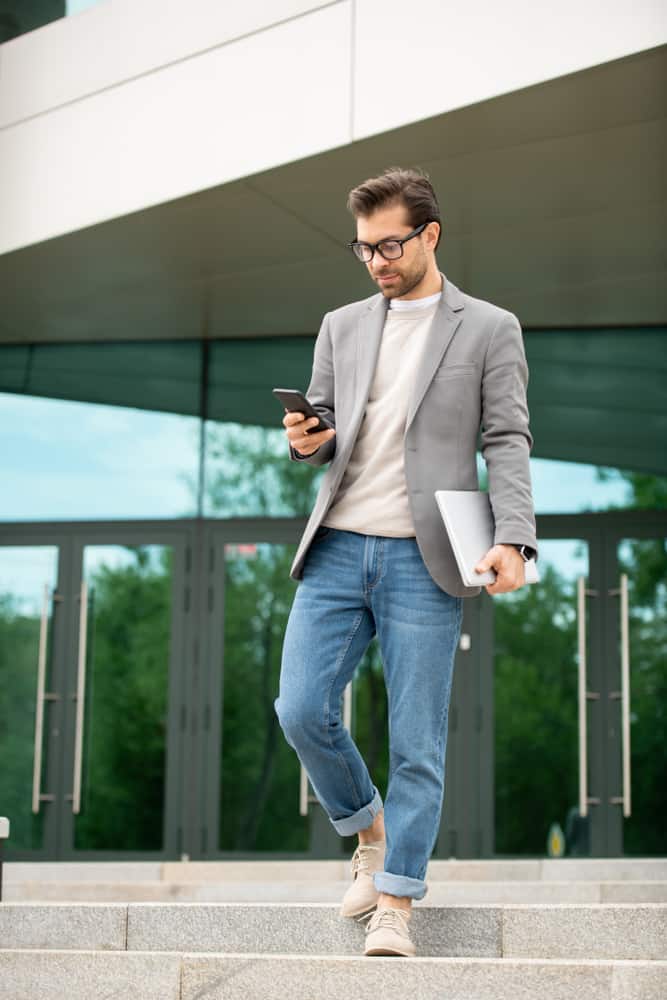 Man in a smart casual texting as he walks down the stairs.