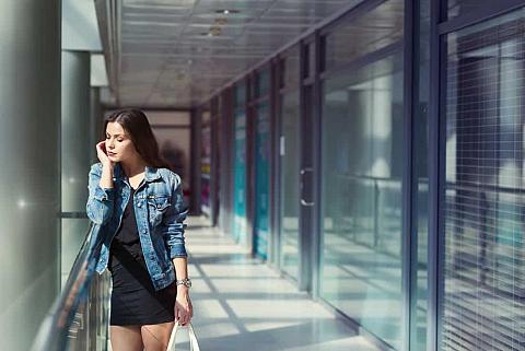 A woman wearing a denim jacket over her little black dress.