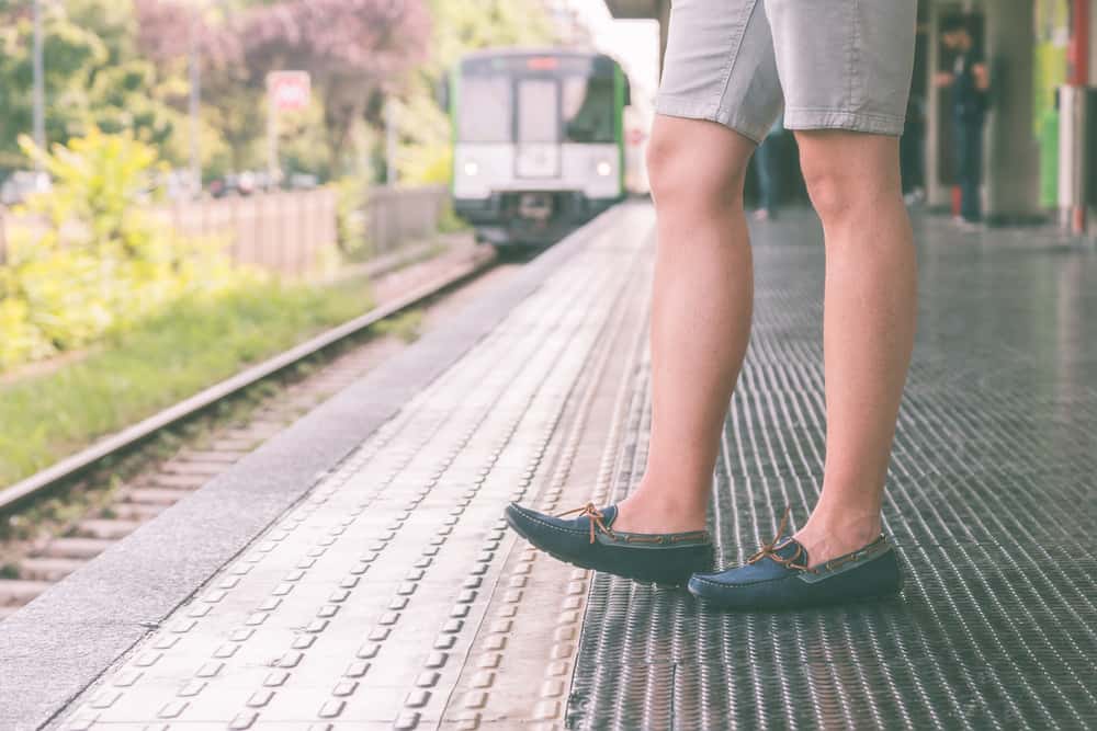 This is a man in the train station wearing shorts and loafers.