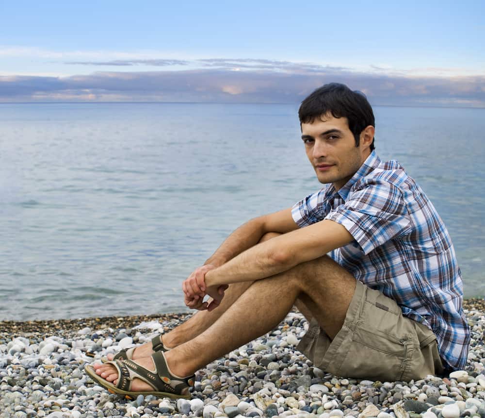A man at the beach wearing khaki shorts and sandals.
