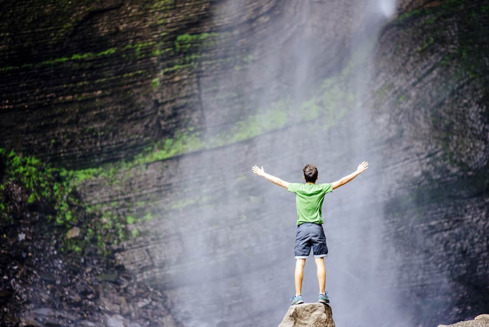 A man wearing shorts gazing at the waterfalls.