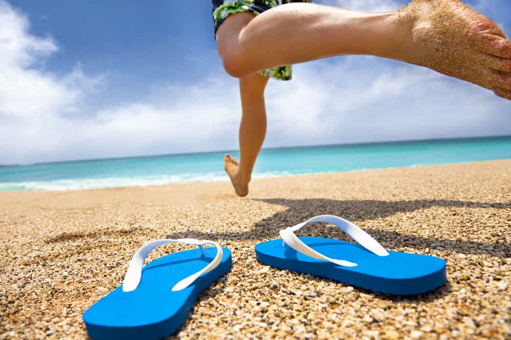 This is a close look at a man leaving his flip-flops by the beach.