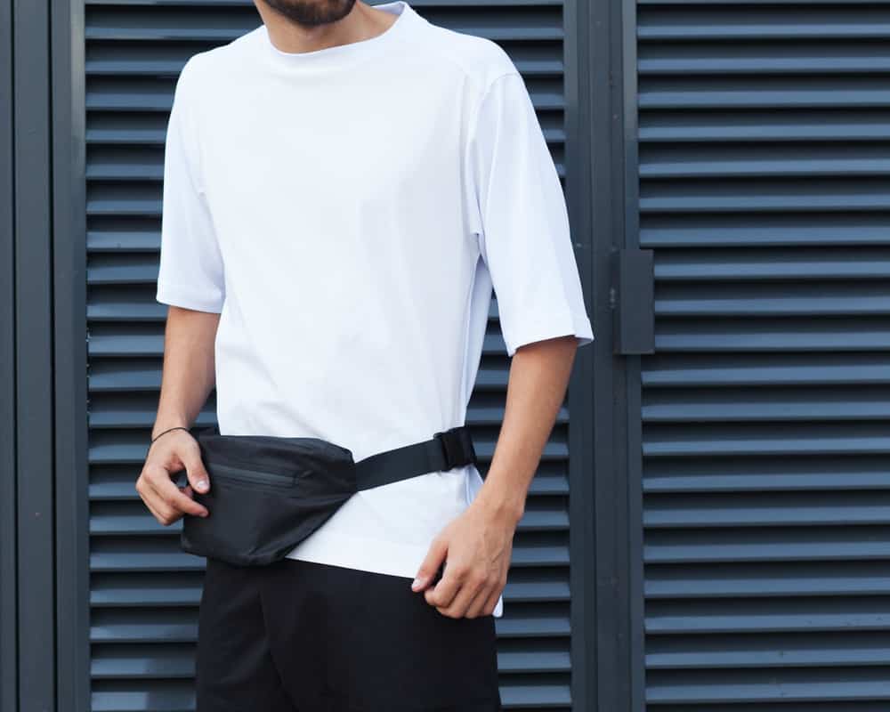 This is a close look at a man wearing a white shirt and a black fanny pack.