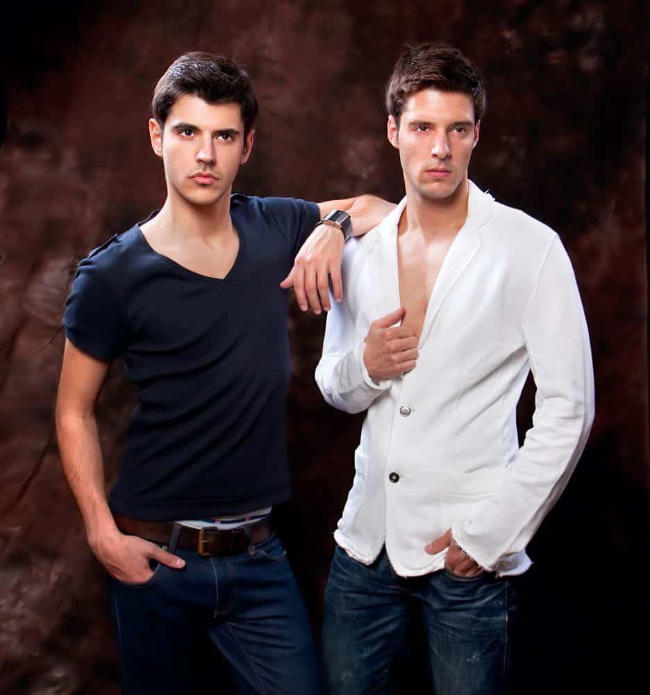 A couple of men wearing shirts and denim pants.