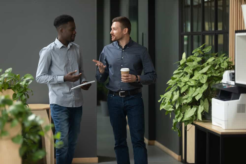 Two men wearing jeans and button-down shirts in an office setting.