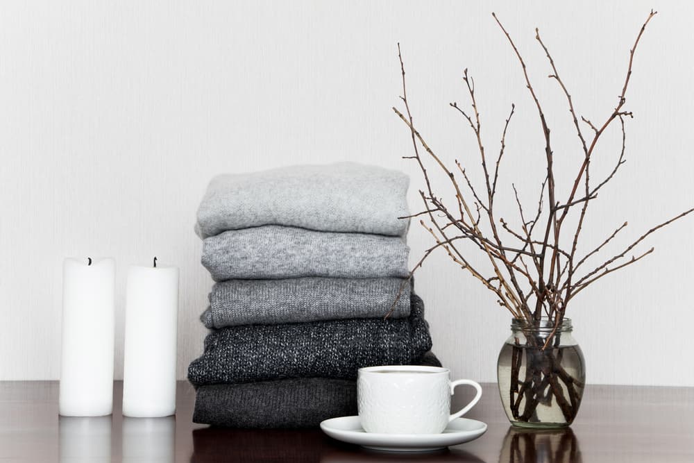This is a pile of folded cashmere sweaters on a wooden table.