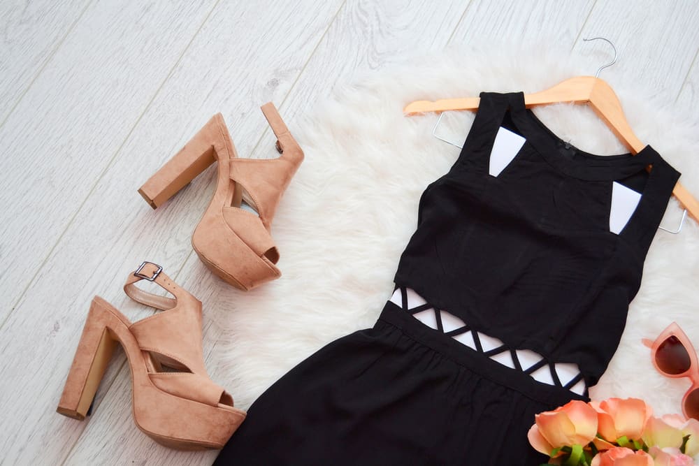 This is a little black dress with a pair of beige heels and sunglasses.