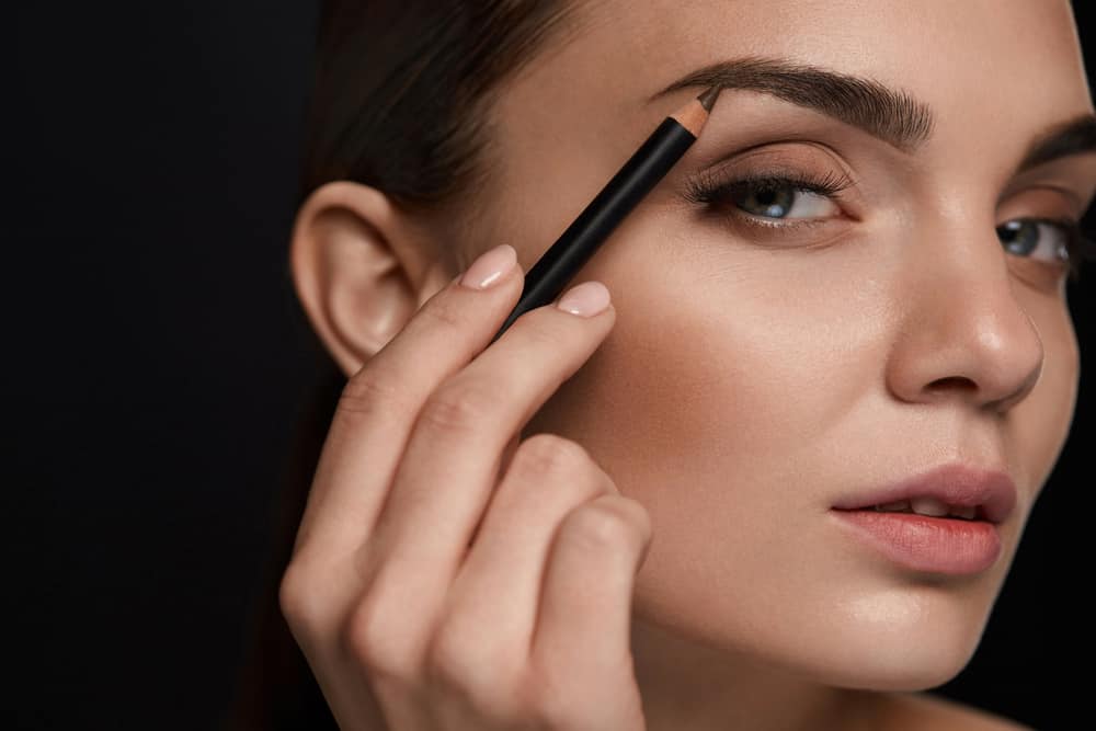 Woman holding an eyebrow pencil.