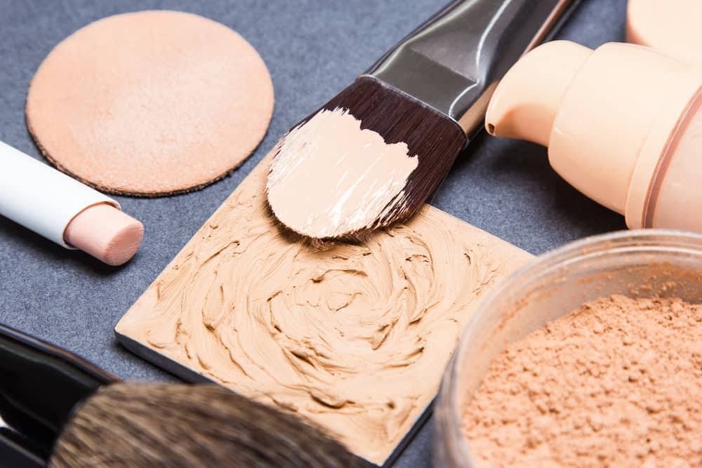 Various types of foundations with makeup brushes.