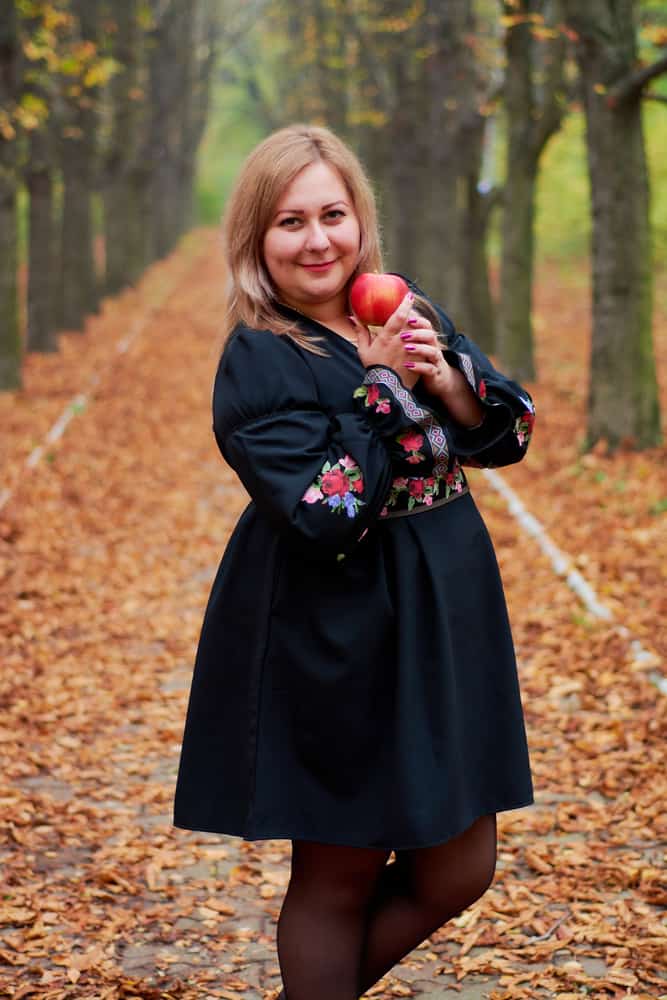 A woman wearing a little black dress with colorful details.