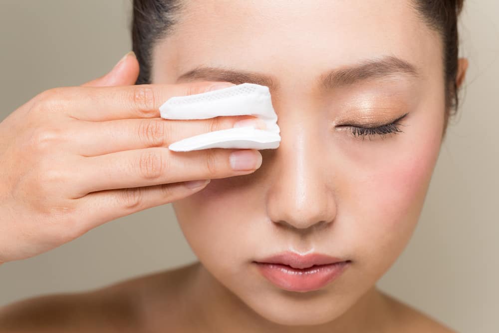 Young woman removing makeup using wipes.