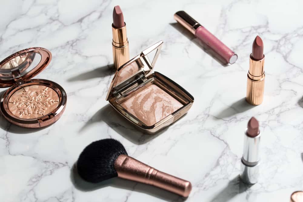 High-end makeup and brush on a white marble table.