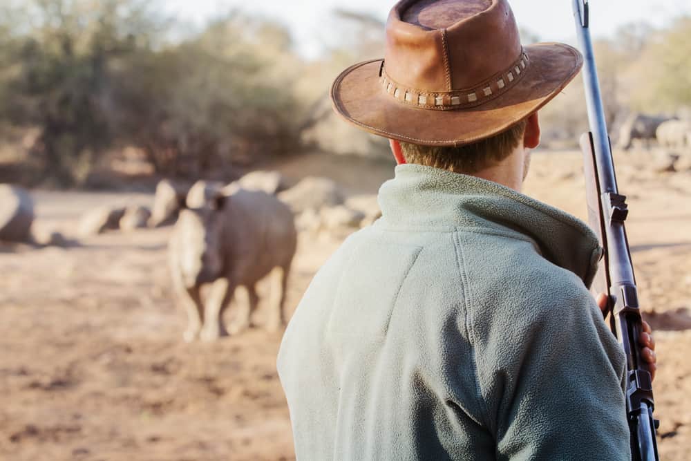 A man wearing a brown campaign hat in an animal preserve.
