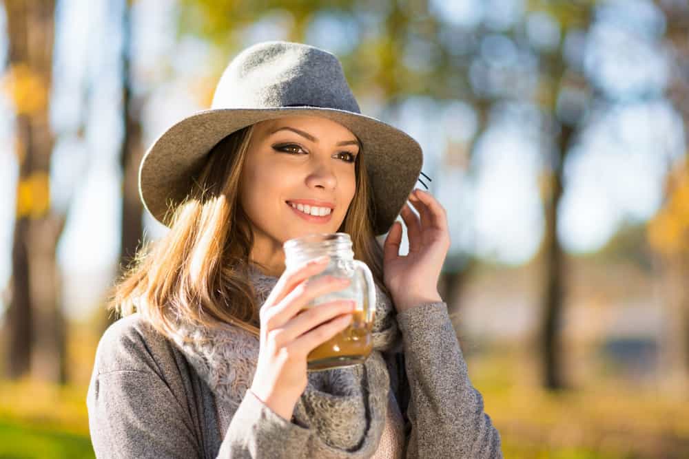 A woman wearing gray clothes and a gray fedora at the park.