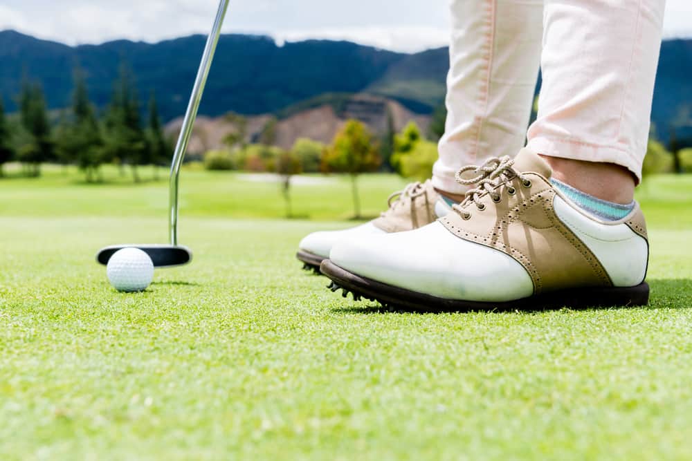 A golfer wearing a pair of golf shoes.