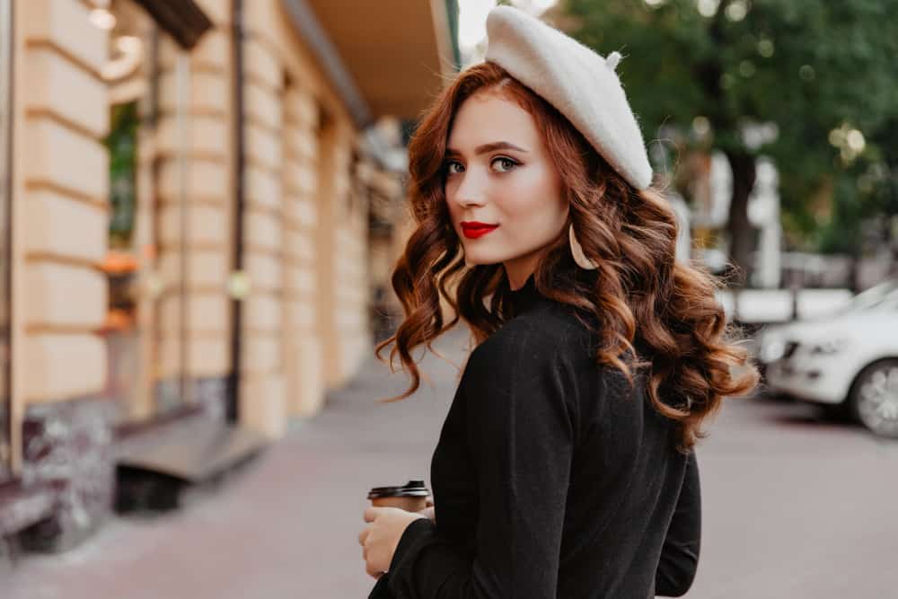 A woman wearing a beret while walking on the sidewalk.