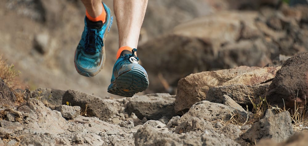 An athlete jogging through the path wearing trail shoes.