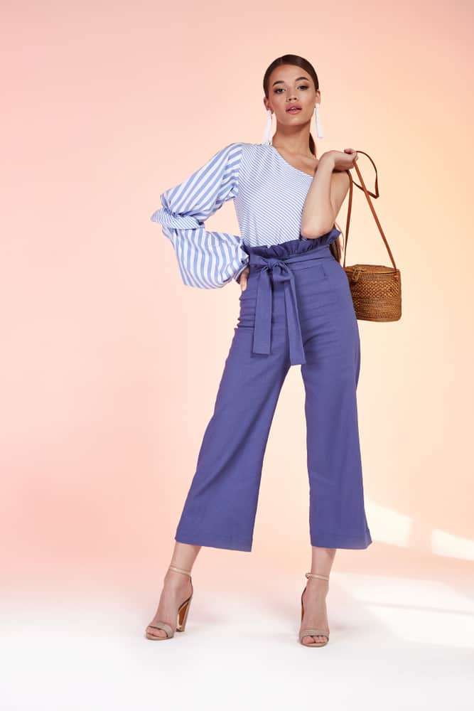 A woman wearing a stylish uneven blouse with her dress pants.